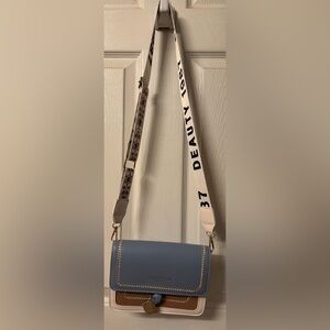 A cute blue and tan purse with floral strap